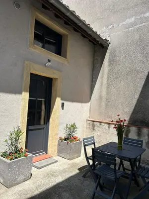 a table and chairs in front of a building with a door at Maison loft au cachet ancien in Villasavary