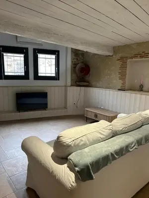 a living room with two beds and a tv at Maison loft au cachet ancien in Villasavary