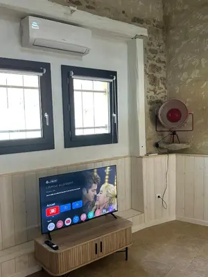 a flat screen tv in a room with two windows at Maison loft au cachet ancien in Villasavary
