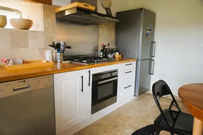a kitchen with white cabinets and a black refrigerator at Volet verts 8 personnes in Fitou