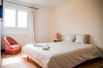 a bedroom with a bed and a chair and a window at Les hauts de Palaja, villa with pool and parking in Palaja
