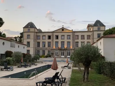 a large building with benches and umbrellas in a courtyard at La Redorte 23 in La Redorte