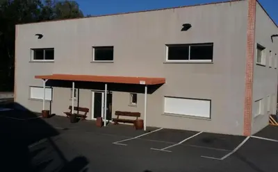 a building with two benches in a parking lot at L'arche rose in Nailloux