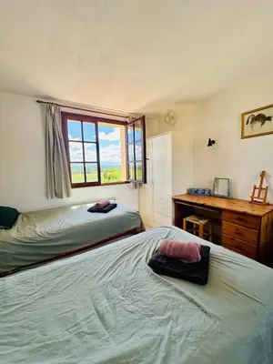 a bedroom with two beds and a desk and a window at La maison du canal in Ventenac en Minervois