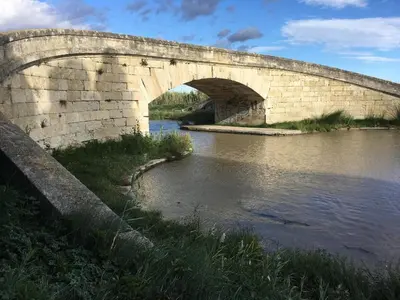 a stone bridge over a body of water at La maison du canal in Ventenac en Minervois
