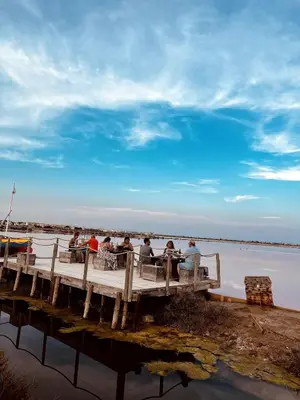 a group of people sitting on a dock near the water at La maison du canal in Ventenac en Minervois