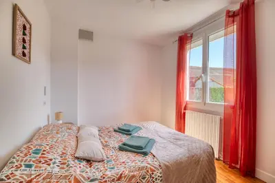 a bedroom with a bed with a red window at La Catalane House T4 Garden Parking in Pamiers
