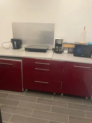 a kitchen with red cabinets and a white counter top at les bambous in Mas-Saintes-Puelles
