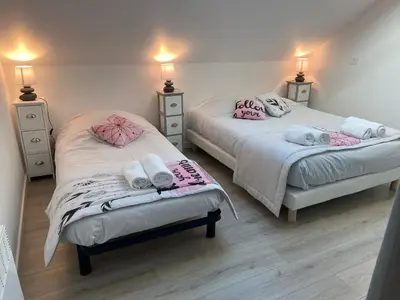 two beds in a room with pink and white towels at Le Grand Gîte in Le Soulié