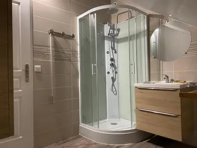 a bathroom with a glass shower and a sink at Le Grand Gîte in Le Soulié