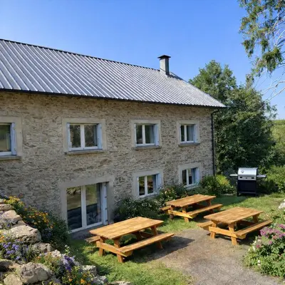 a stone building with picnic tables in front of it at Le Grand Gîte in Le Soulié