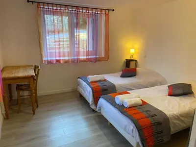 a bedroom with two beds and a table and a desk at Le Grand Gîte in Le Soulié