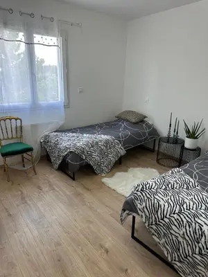 a room with two beds and a chair and a window at La Maison Belle Étoile in Limoux