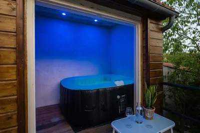 a hot tub on a deck with a table at La Bastide - Terrasse - Jacuzzi in Carcassonne