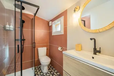 a bathroom with a toilet and a sink and a mirror at La Bastide - Terrasse - Jacuzzi in Carcassonne