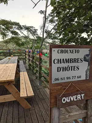 a sign on a wooden deck with two picnic tables at CROUXETO Chambres d'hôte in Duilhac