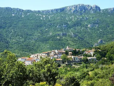 a town on a hill with mountains in the background at CROUXETO Chambres d'hôte in Duilhac