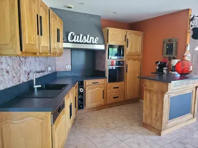 a kitchen with wooden cabinets and a black counter top at Villa privée au calme avec gand jardin et terrasse in Bout-du-Pont-de-Larn