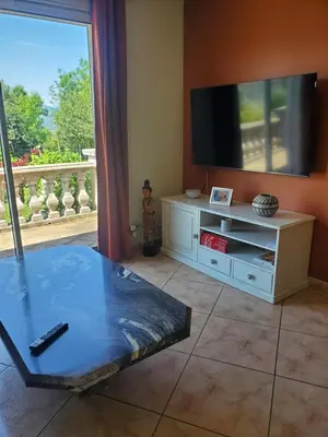 a living room with a tv and a table at Villa privée au calme avec gand jardin et terrasse in Bout-du-Pont-de-Larn