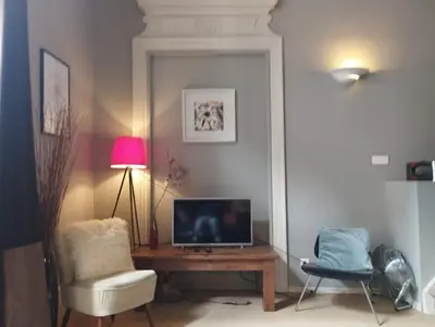 a living room with a tv and a table and a chair at The Cozy 42 stylish apartment in Carcassonne