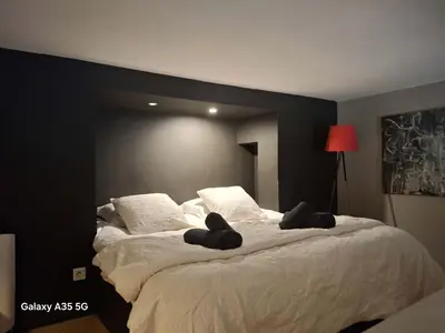 a bedroom with a large white bed with black walls at The Cozy 42 stylish apartment in Carcassonne