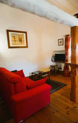 a living room with a red couch and a piano at Albizia in La Redorte