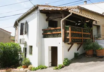 a white house with a balcony with plants at Albizia in La Redorte