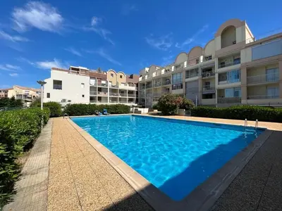 a large swimming pool in front of a building at Apt de charme 4 pers, vue port, location idéale in Gruissan