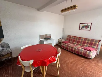 a living room with a red table and a couch at Pavillon cosy 6 pers Patio privé et plage à pied in Port-la-Nouvelle