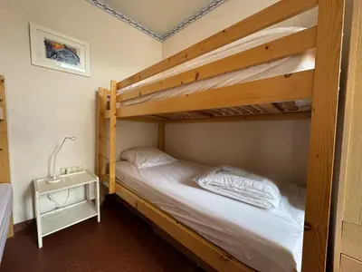 a bedroom with two bunk beds and a night stand at Pavillon cosy 6 pers Patio privé et plage à pied in Port-la-Nouvelle