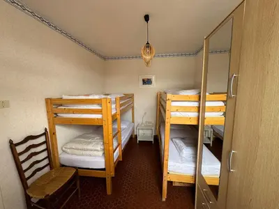 a room with three bunk beds and a chair at Pavillon cosy 6 pers Patio privé et plage à pied in Port-la-Nouvelle