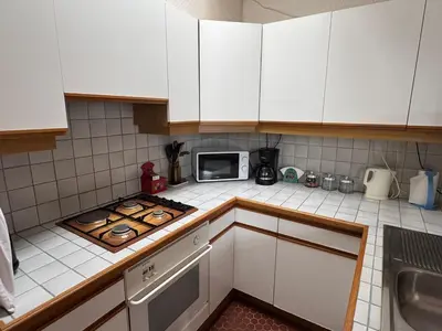 a kitchen with white cabinets and a microwave at Pavillon cosy 6 pers Patio privé et plage à pied in Port-la-Nouvelle