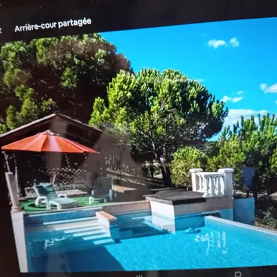 a tv screen showing a swimming pool and an umbrella at Chez Hélène et Michel in Preixan