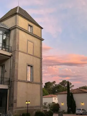 a building with a clock tower in front of a sunset at la redorte 25 in La Redorte