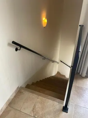 a staircase with a light on the wall and a stair railing at La Redorte 28 in La Redorte