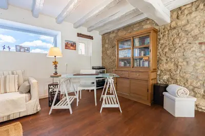 a living room with a stone wall and a table and stools at L'Échappée Belle - Grande Maison, Jardin & Piscine in Castres
