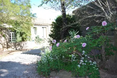 a garden with pink flowers in front of a house at maison des Géraniums in Trausse