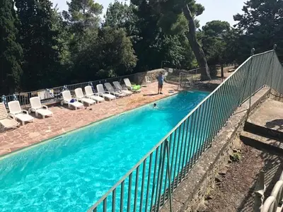 a person standing next to a fence next to a swimming pool at maison des Géraniums in Trausse