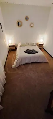 a bedroom with a white bed and two night stands at Le nid du canal in Pezens