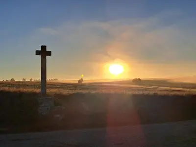 a cross on the side of a field with the sunset at Le nid du canal in Pezens