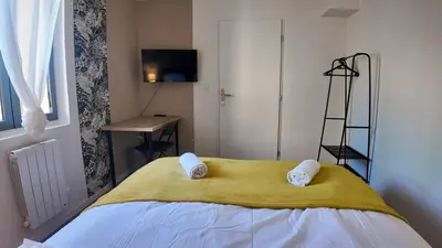 a bedroom with a bed with a yellow blanket and a desk at Elégant Appartement - 2 Chambres - Netflix - Terrasse in Castres