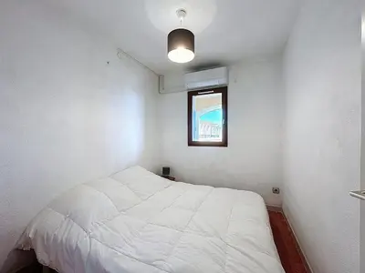 a small bedroom with a white bed and a window at Le Thalio - Swimming pool - Air conditioning in Gruissan