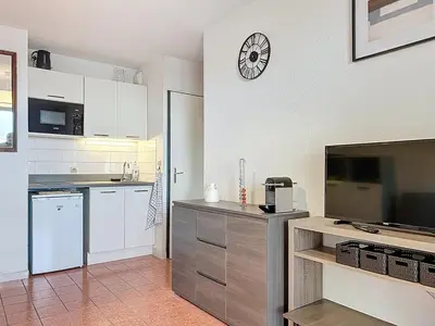 a kitchen with white cabinets and a clock on the wall at Le Thalio - Swimming pool - Air conditioning in Gruissan
