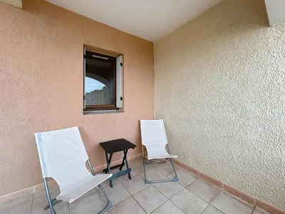 two white chairs and a table in a room at Le Thalio - Swimming pool - Air conditioning in Gruissan