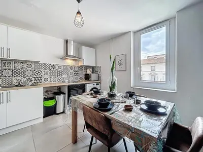 a kitchen with a table and chairs in a kitchen with a window at Le Bohja - Charming apartment near Les Halles in Narbonne