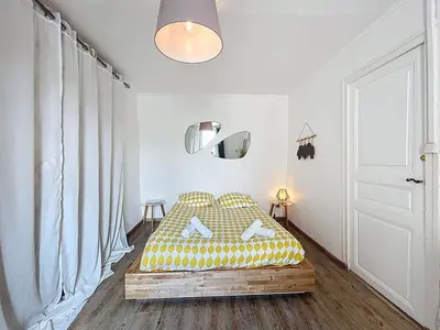 a bedroom with a bed and a large window at Le Bohja - Charming apartment near Les Halles in Narbonne