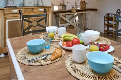 a wooden table with plates of food and bowls of fruit at Charme, confort en centre-ville in Limoux