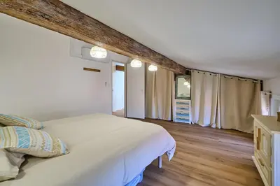 a bedroom with a large white bed and wooden floors at Charme, confort en centre-ville in Limoux