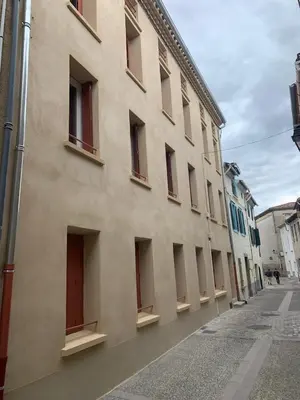 a large building with red windows on a street at Charme, confort en centre-ville in Limoux