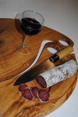 a wooden cutting board with a knife and a glass of wine at L'Echiquier in Castres